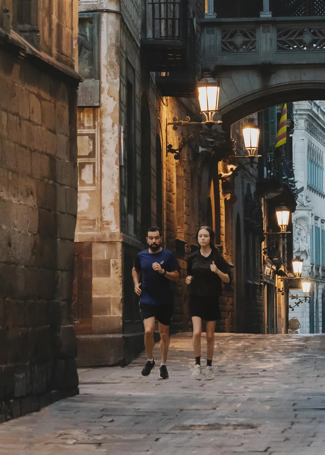 Dos personas corriendo al amanecer por una calle del Barrio Gótico de Barcelona
