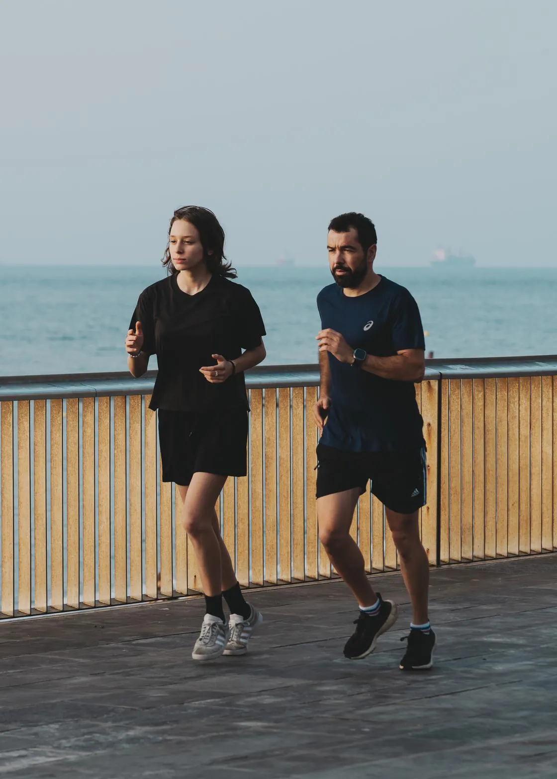 Dos personas corriendo juntas por el paseo marítimo de Barcelona